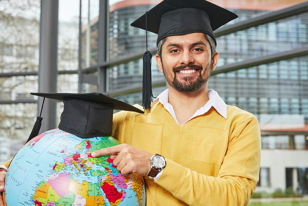 Absolvent mit einem Globus im Arm
